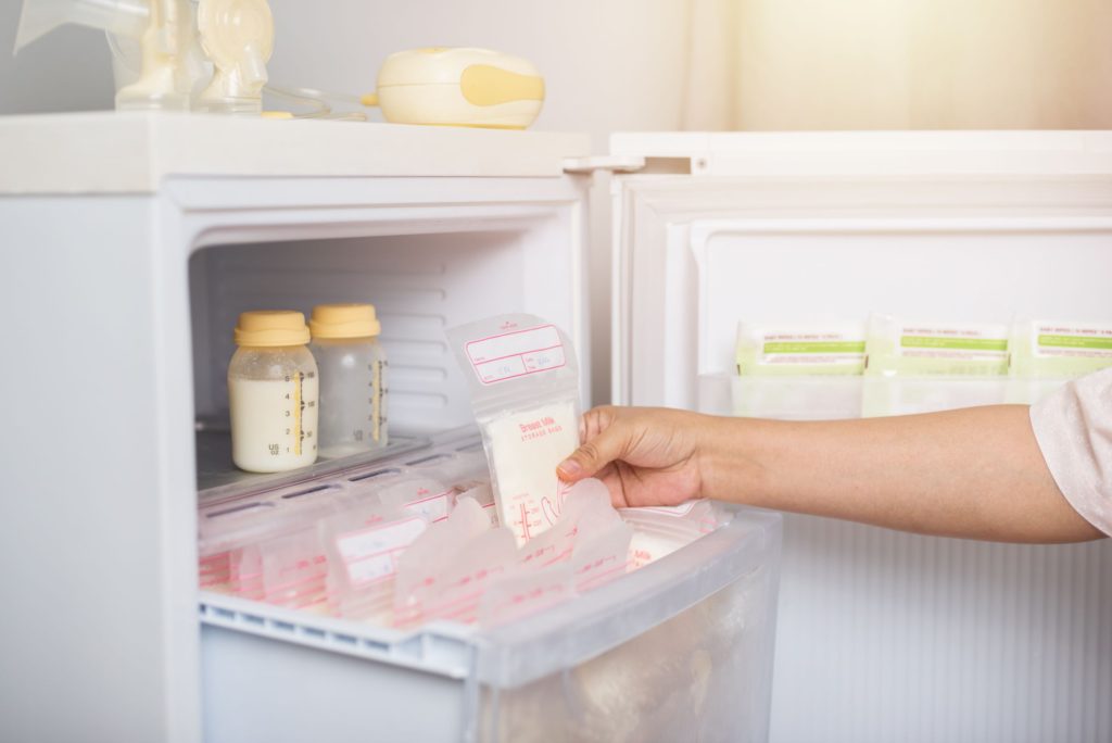 Woman picking out stored breast milk from freezer