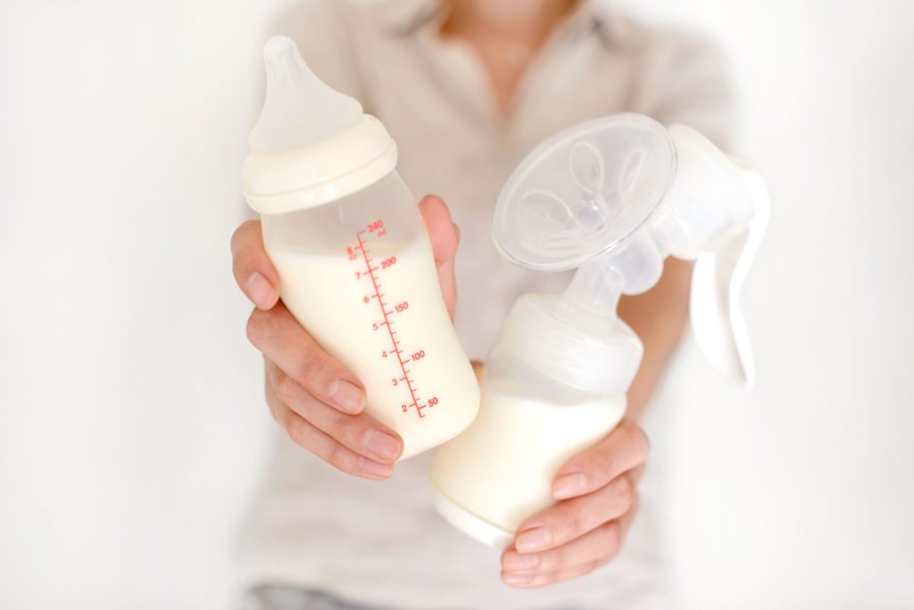 Woman holding a bottle of milk and breast pump