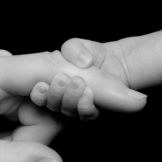 Newborn holding adult finger