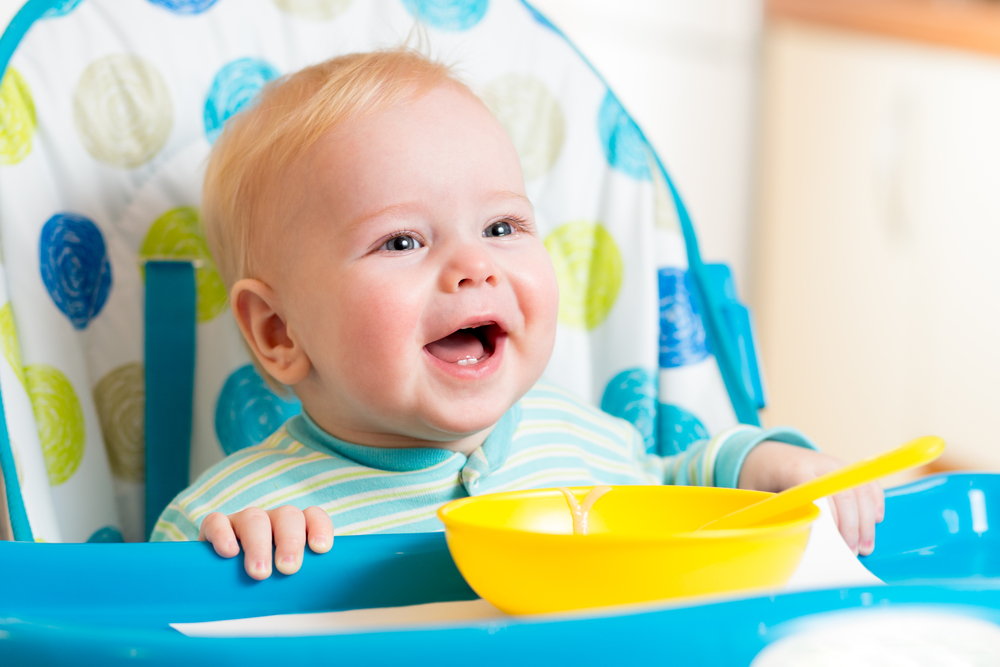 Baby sat in highchair eating and smiling