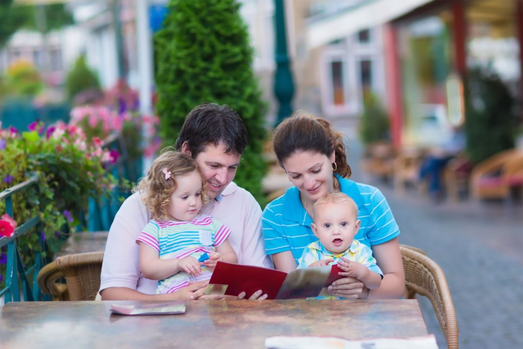 A family with toddlers looking at a menu on an outdoor table