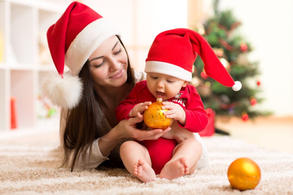 Mum and baby in Santa hats holding a bauble