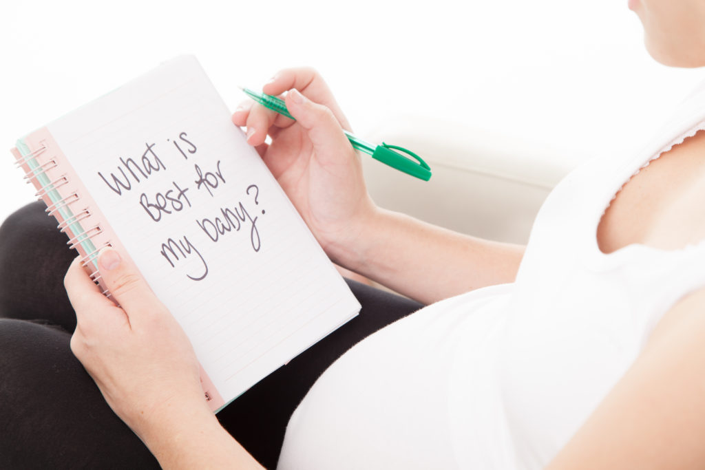 Pregnant woman writing in her diary about what is best for her baby 