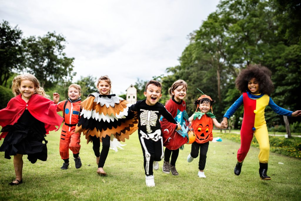 Row of children having fun and running outside whilst dressed up in Halloween costumes