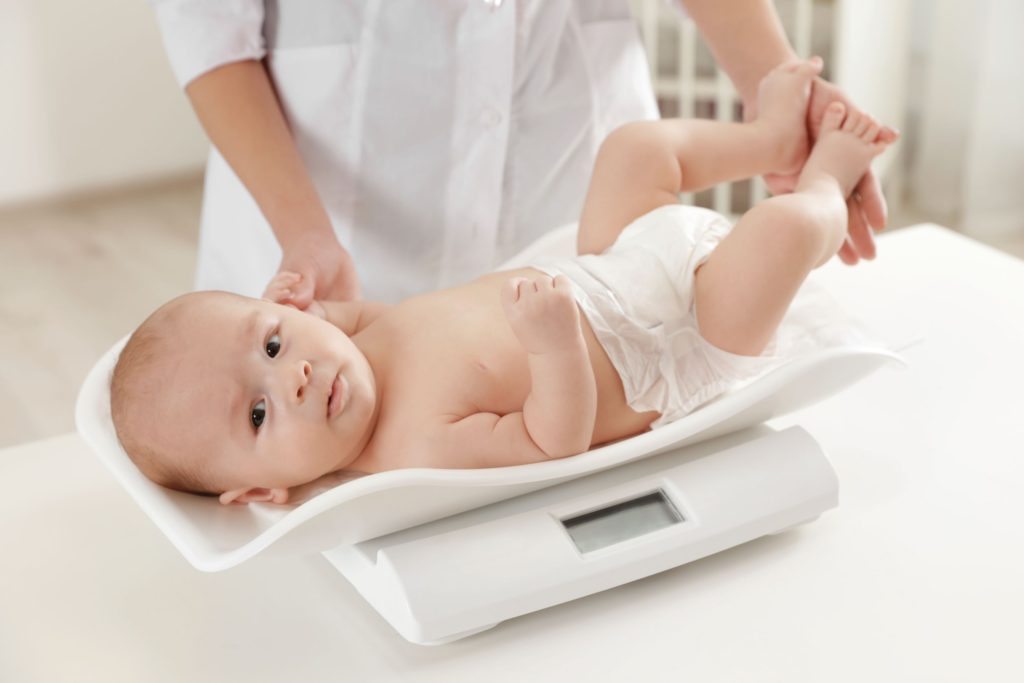 Baby on weighing scales looking at camera