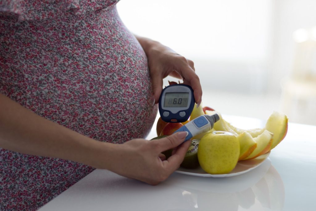 Pregnant woman holding insulin measurer