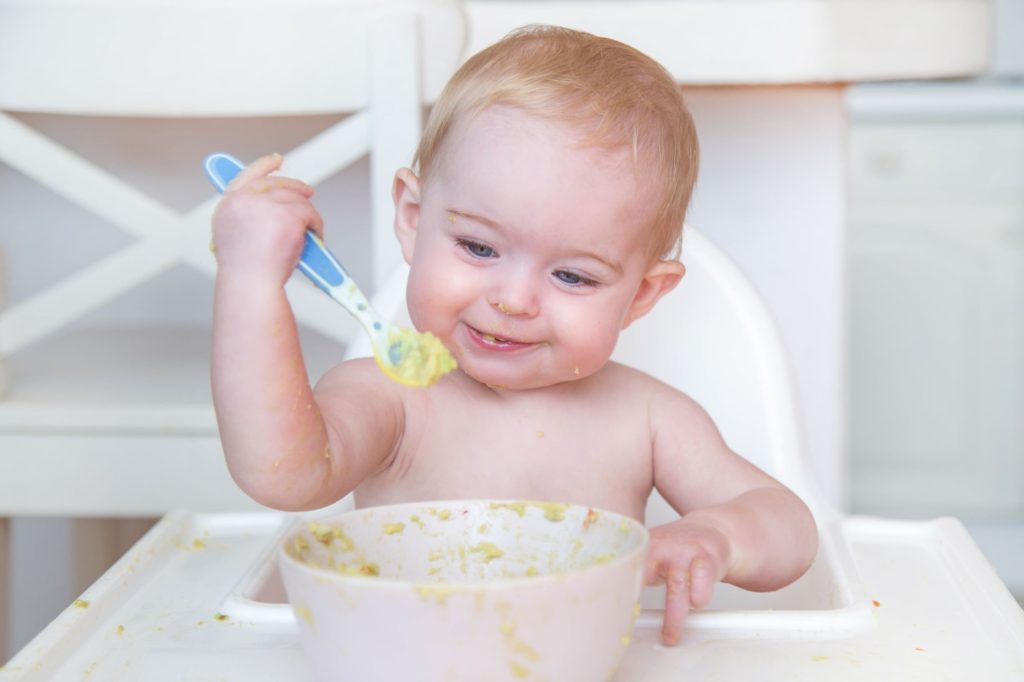 Happy, smiling baby eating porridge