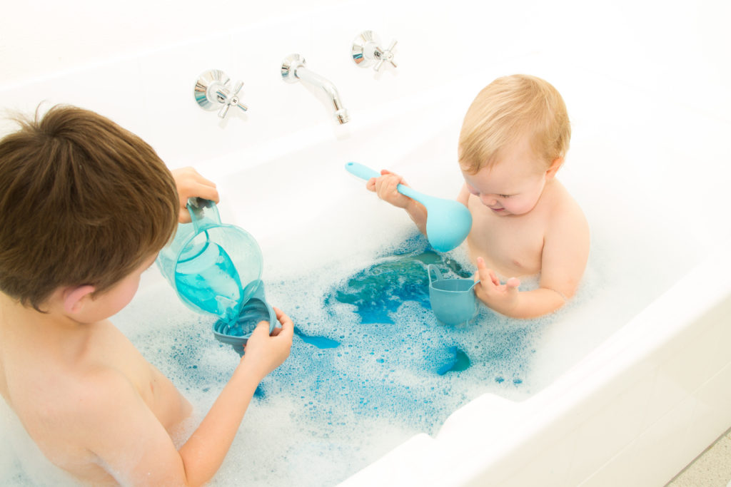 Baby and older sibling playing in the bath together