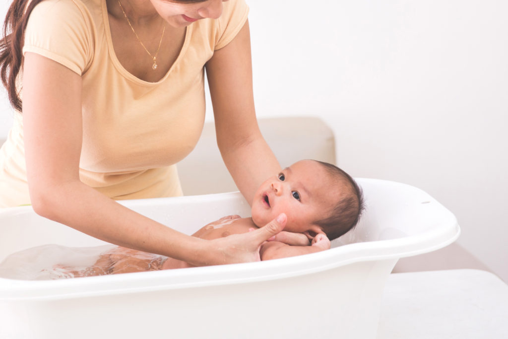 Mum looking down and holding newborn in baby bath
