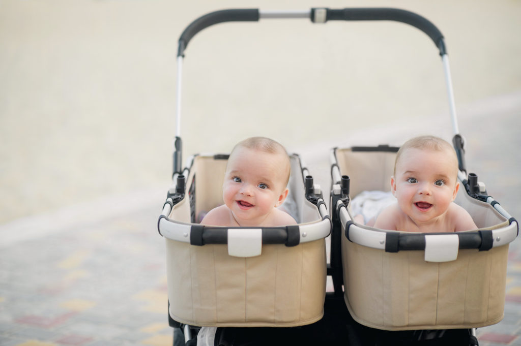 Twin babies in their prams looking happy and smiley