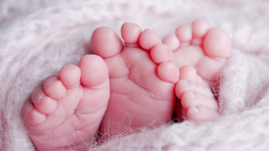 Close up of twin baby toes wrapped up in a blanket