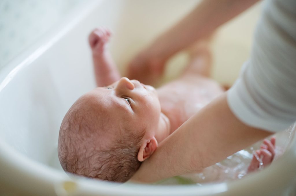 Newborn baby being bathed by mother