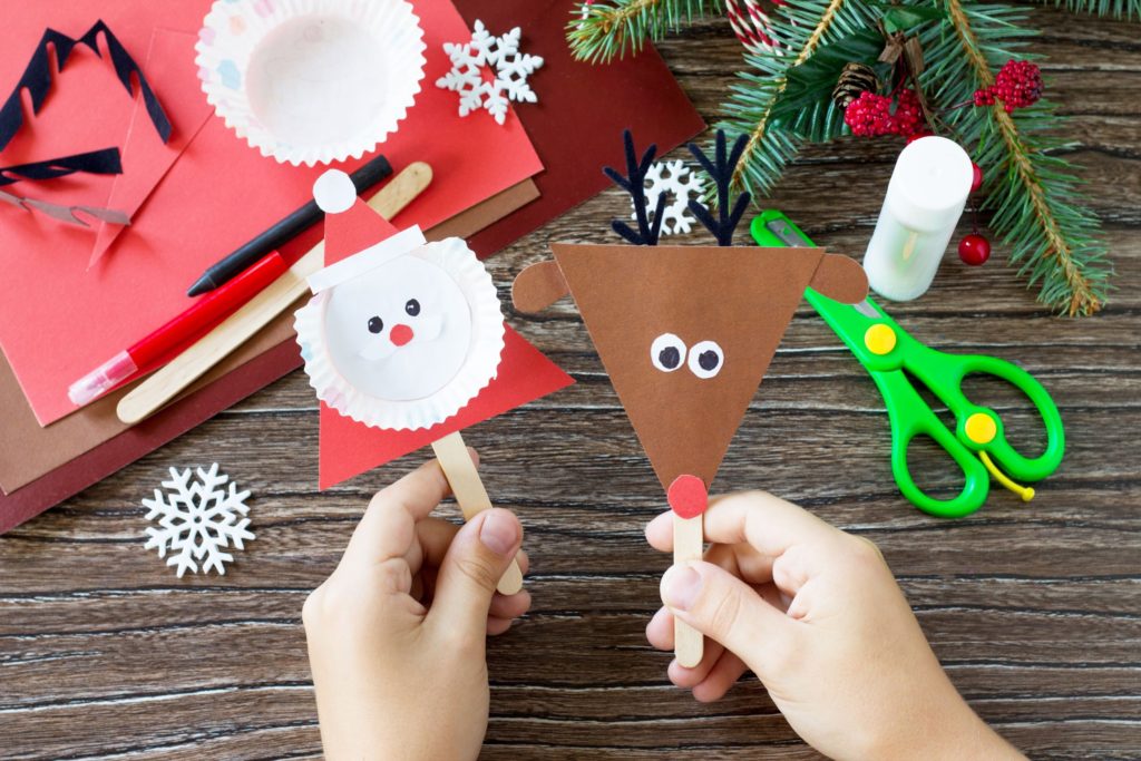 Santa and reindeer lolly stick crafts being held by a child