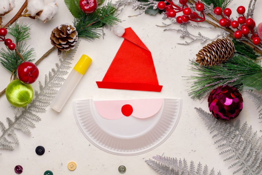 Paper plate Santa mask surrounded by Christmas decor
