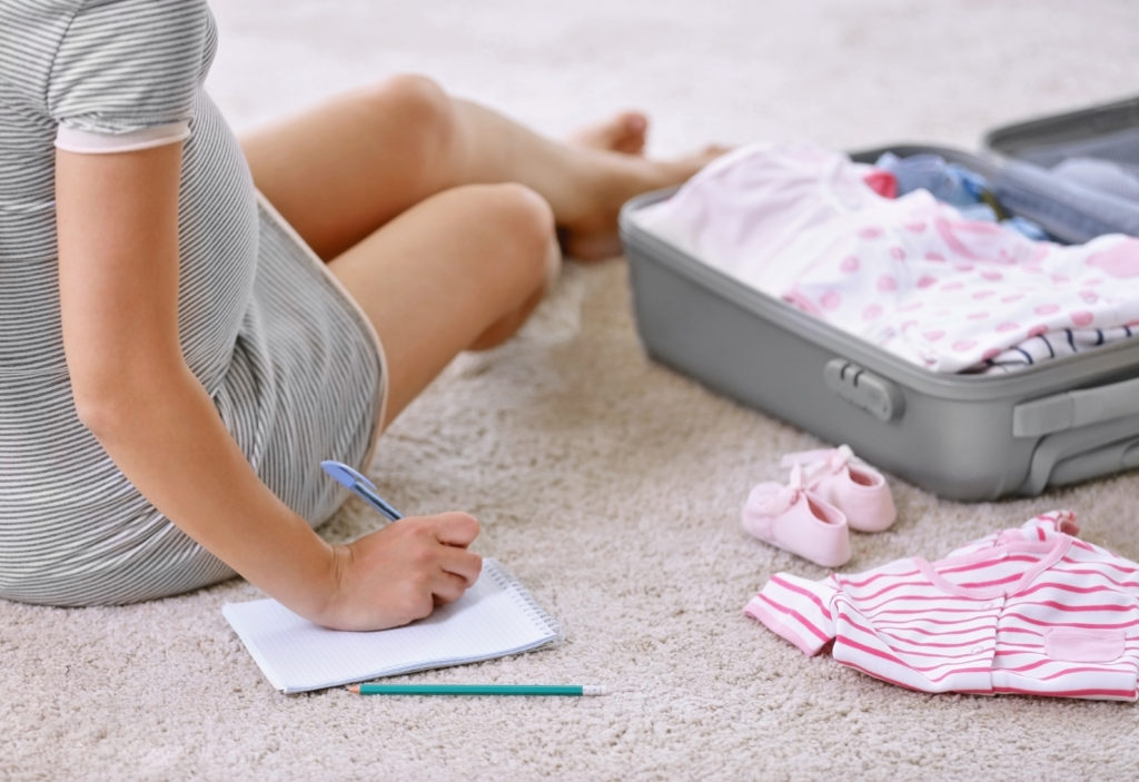 Woman ticking off her hospital bag checklist whilst packing