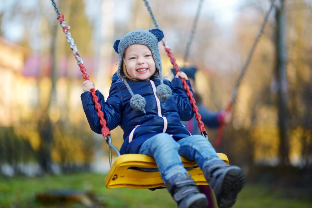 Little girl grinning on swing