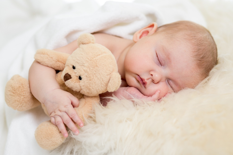 sleeping baby cuddling a teddy bear