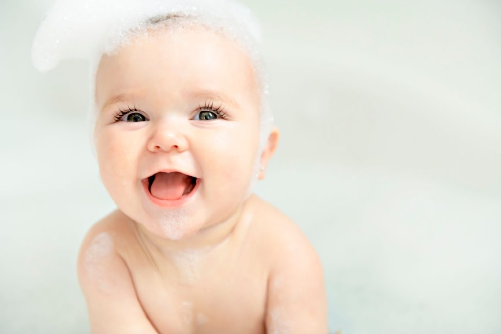 Cute baby giggling with soap suds on their head