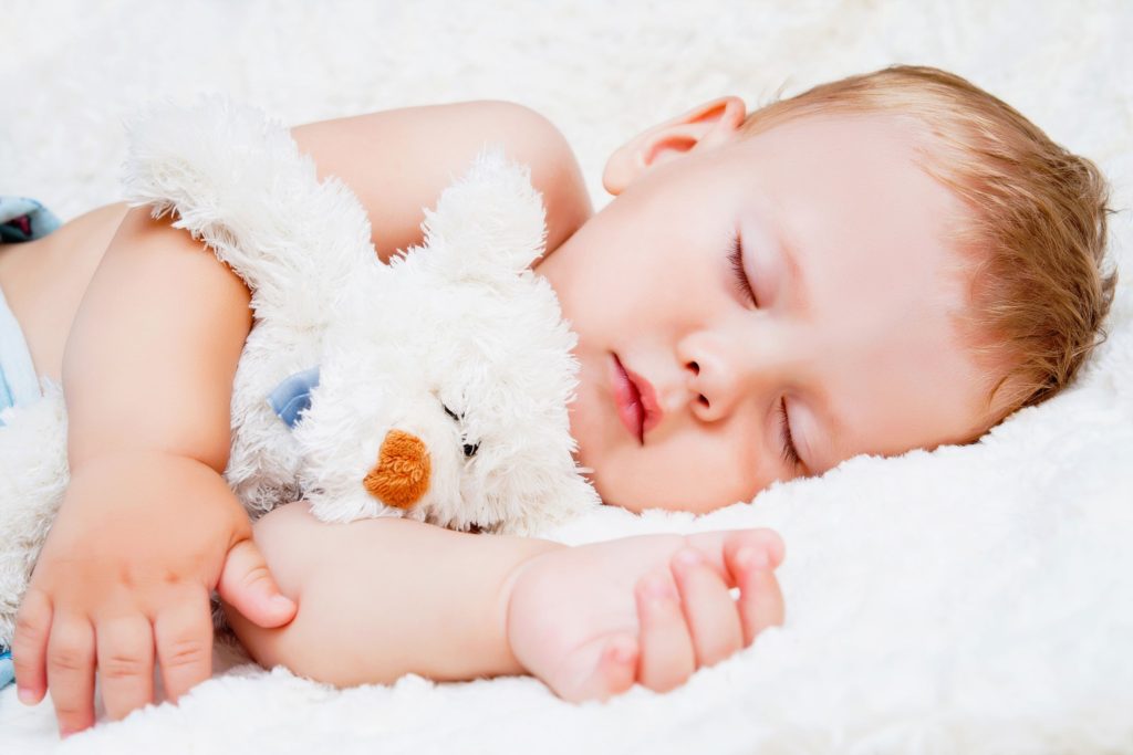 baby sleeping holding a teddy