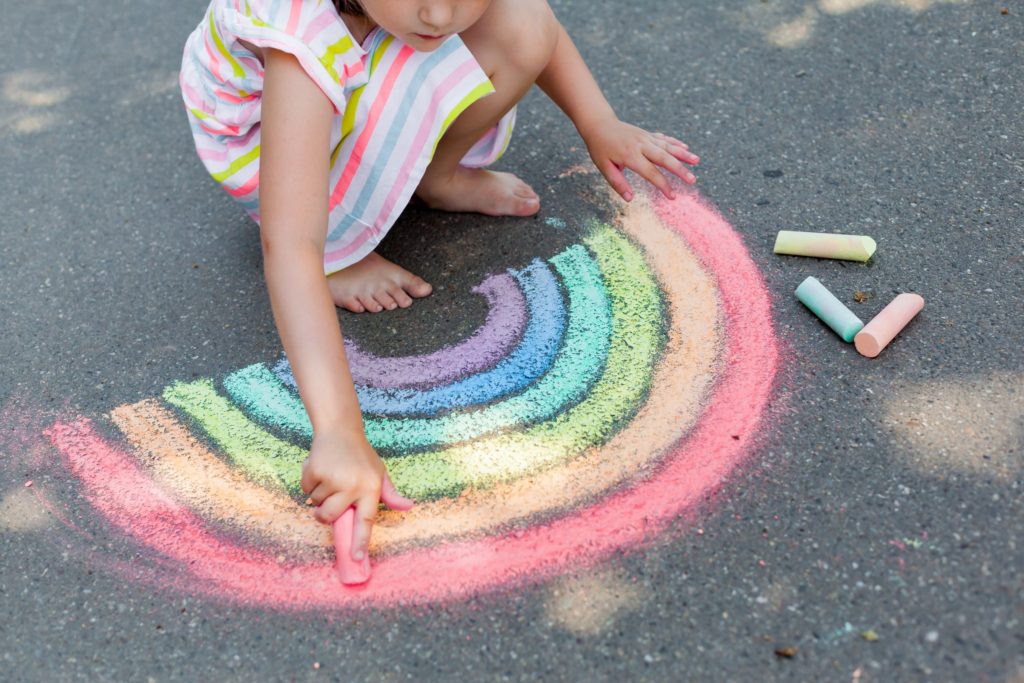 A child drawing a rainbow in chalk