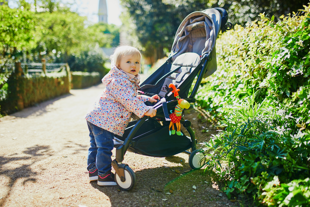 Adorable,Happy,Toddler,Girl,Standing,Next,To,Her,Pushchair,In
