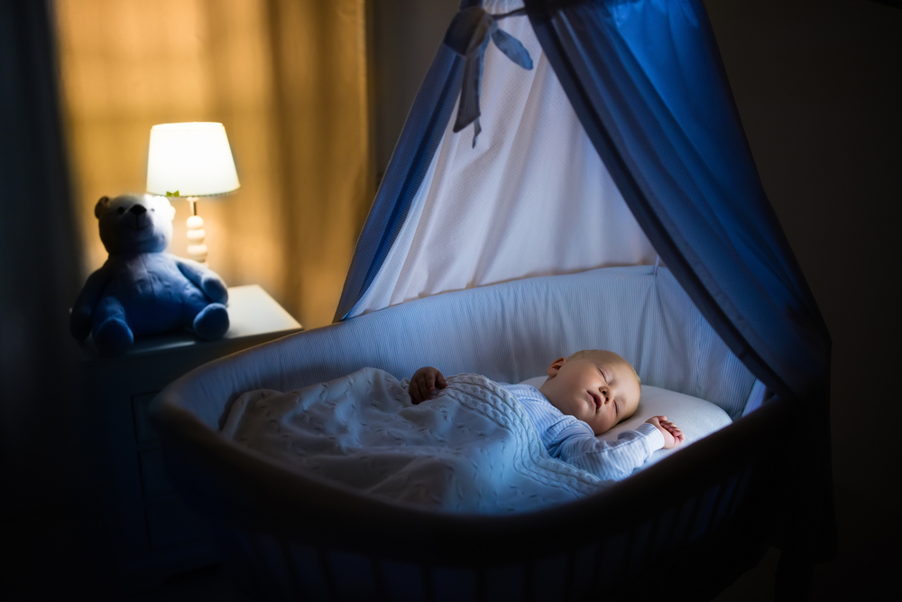 Adorable Baby Sleeping In Blue Bassinet With Canopy At Night