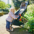 Adorable,Happy,Toddler,Girl,Standing,Next,To,Her,Pushchair,In
